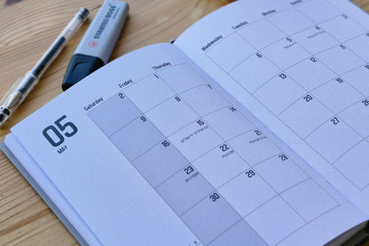 Calendar on a wooden surface with a pen and small container