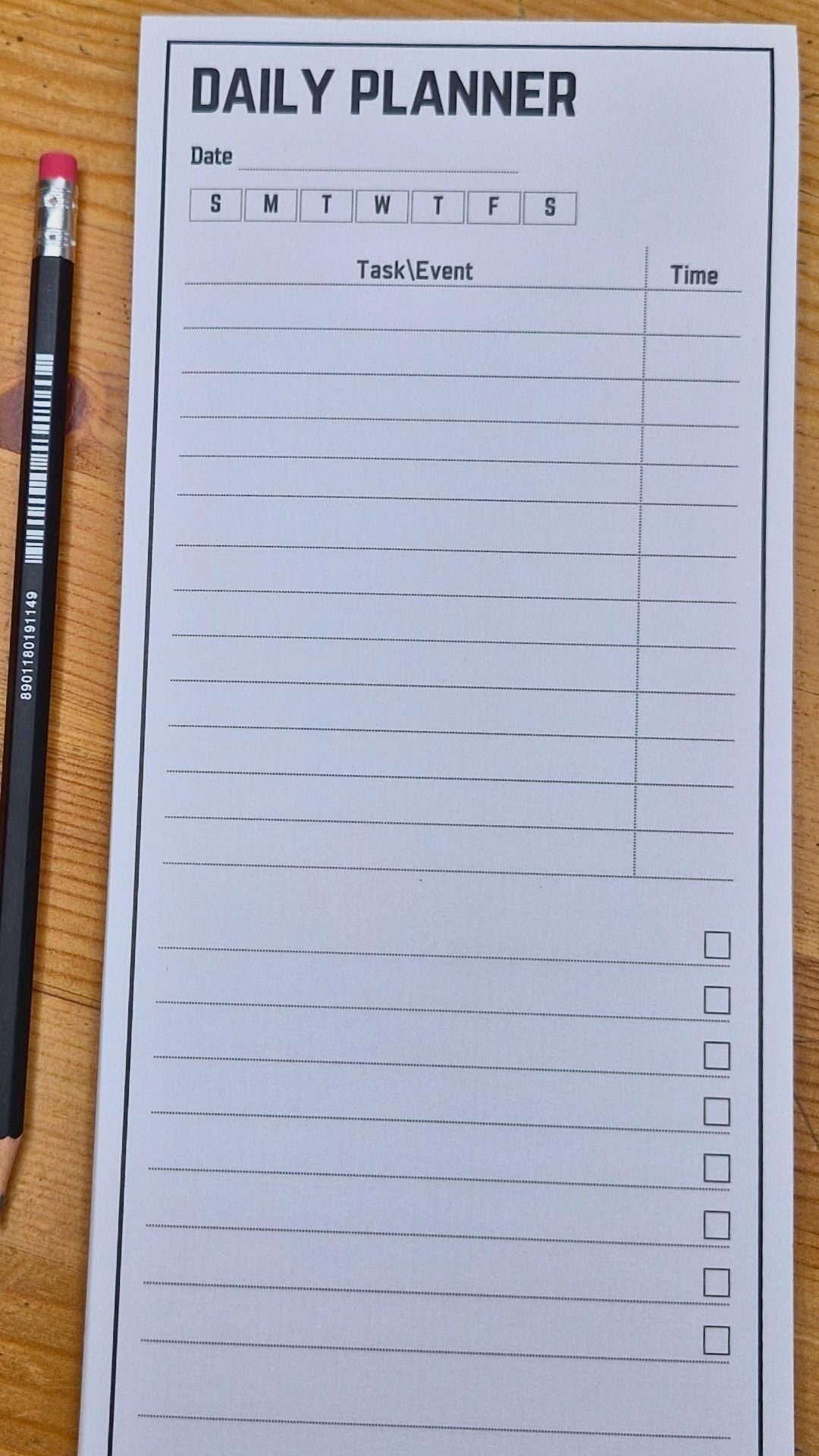 Daily planner with checkboxes and a pencil on a wooden surface