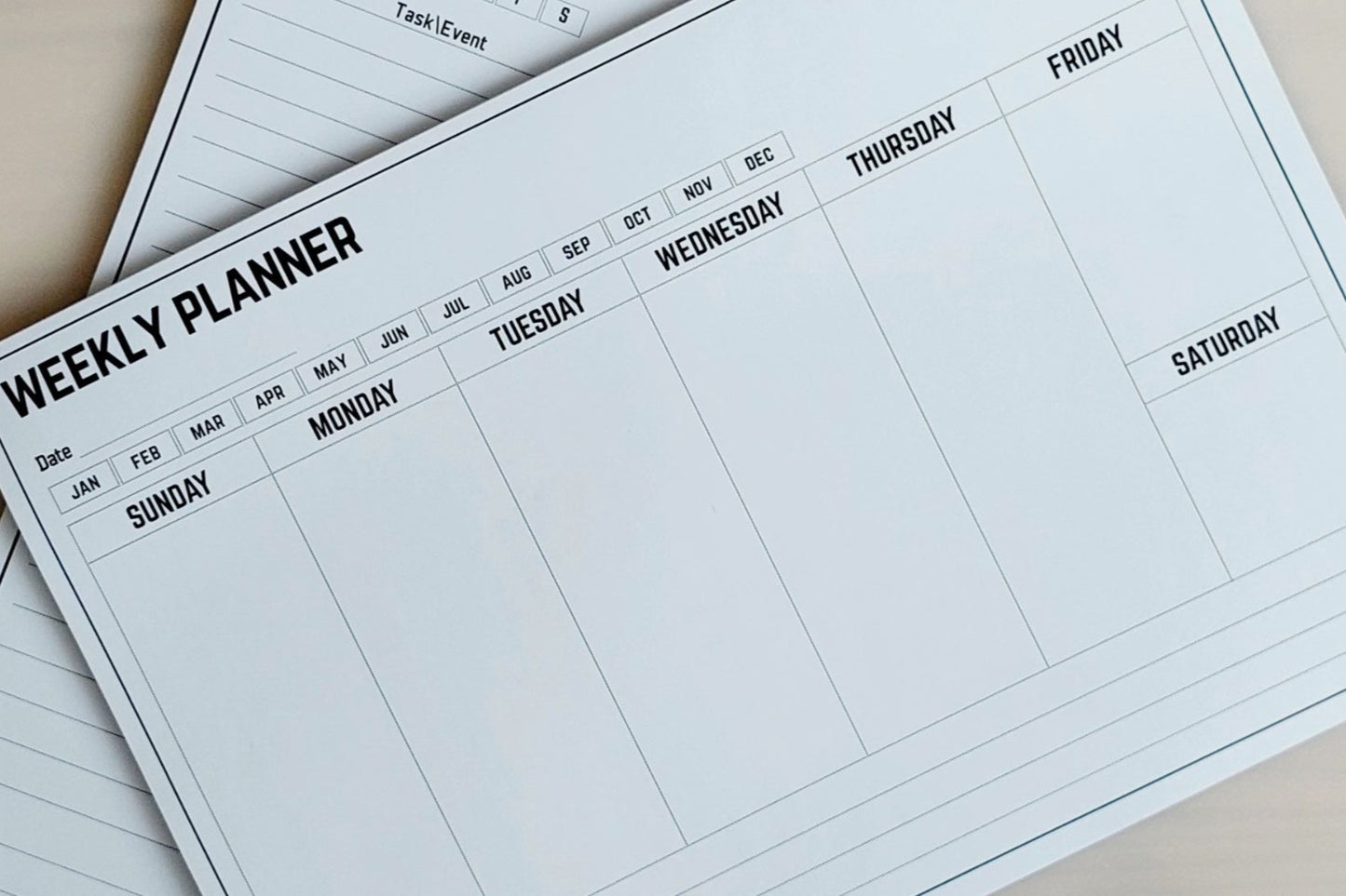 Weekly planner with days of the week on a beige surface